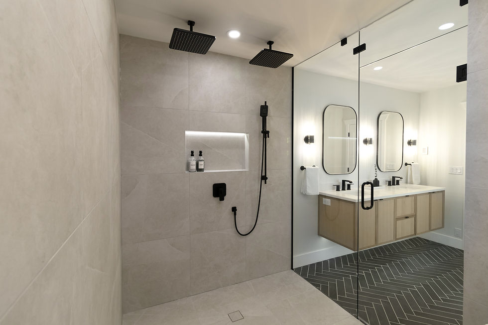 Modern bathroom with glass shower, dual rain shower heads, and built-in shelves. Light wood vanity with double sinks and mirrors.