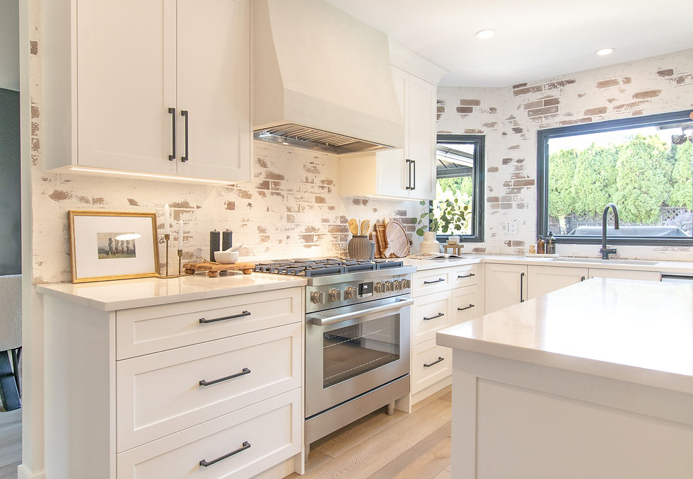 Bright kitchen with white cabinets, brick backsplash, stainless steel stove, and wooden utensils. Large windows and plastered rangehood.