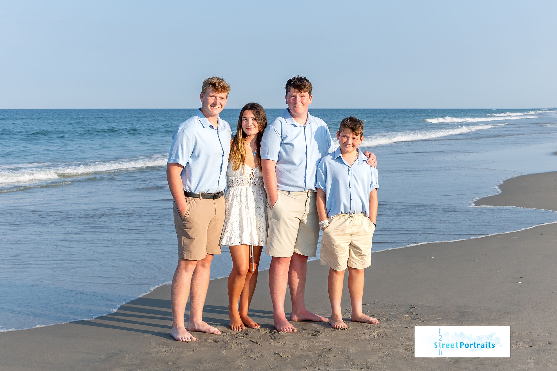 A girl and her three brothers stand by the water on the beach in Corolla, NC
