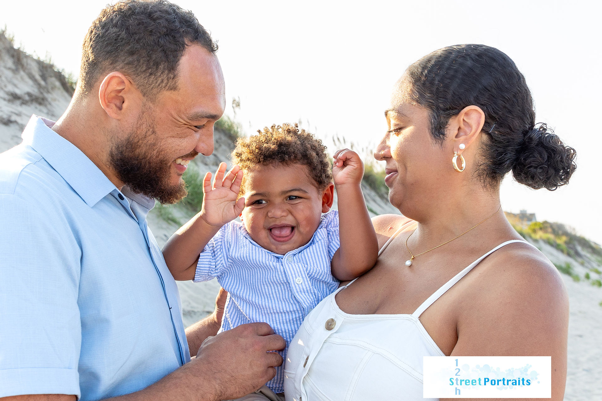 A baby laughs with his parents on the beach in Corolla, NC
