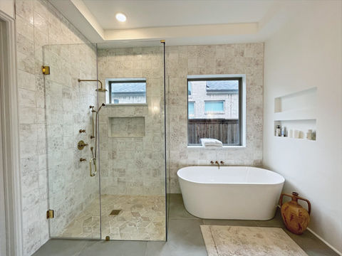 Spacious shower and tub combo with glass enclosure and neutral tilework by FERCO Construction & Remodeling in Celina, Texas
