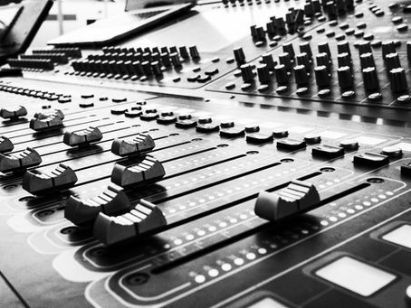 Close-up of a professional audio mixing desk with faders and controls, representing voiceover studio equipment