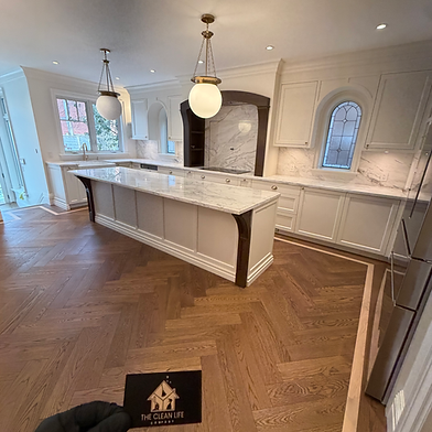 Kitchen with a marble island and pendant lights after a post-renovation clean