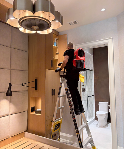 Cleaner on a ladder dusting built-ins after a renovation