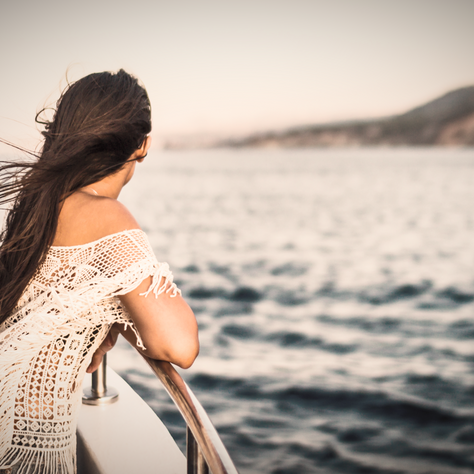 Solo woman looking out from a cruise ship a the mountains and shore
