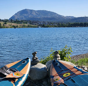 Two paddleboards by Okanagan Lake, rock cairns, mountain view