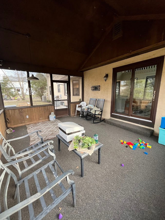 Eye-level view of a rundown screen porch with peeling paint and torn screens