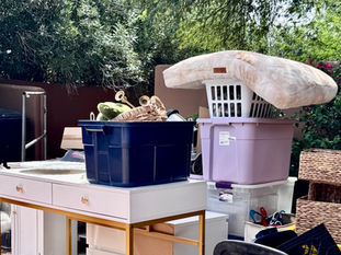 Household items, furniture, and storage bins sorted outside a Phoenix home during a decluttering project