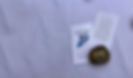 Stones with Christian carvings on the stones scattered on a white table cloth.  White cards on the table, one with the episcopal church on Staten Island logo and the other with a prayer attributed to St. Francis. 
