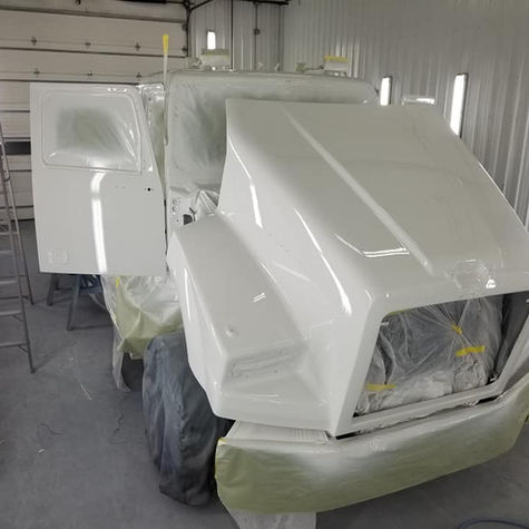 Freshly painted white heavy vehicle in a professional spray booth.