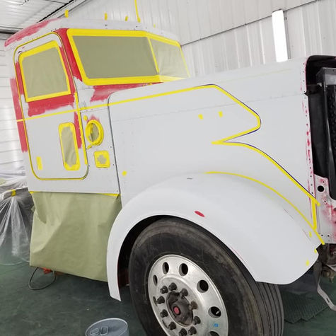 Semi-truck cab and front end prepped for custom paint in a booth.