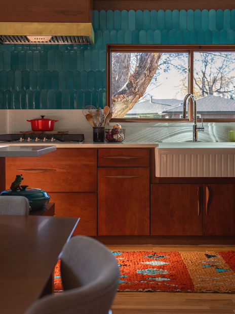 Warm kitchen in Wheat Ridge, Colorado, with teal backsplash, farmhouse sink, and a colorful rug.