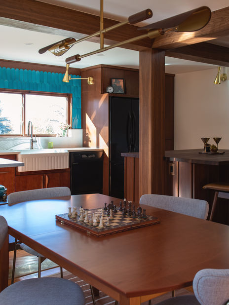 Mid-century style dining area in Wheat Ridge, Colorado, with a wood table and teal tile kitchen in the background.