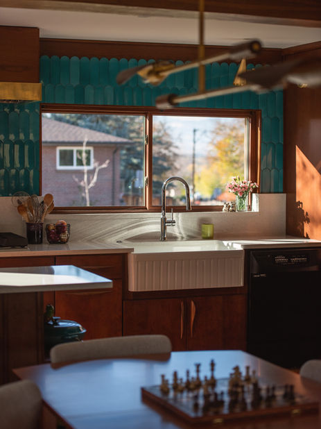 Kitchen in Wheat Ridge, Colorado with teal backsplash, farmhouse sink, and a chess board on the table.