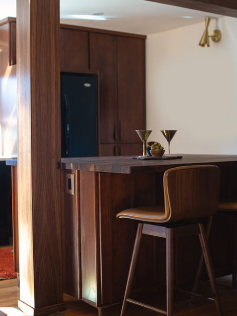Small bar area in a Wheat Ridge home with wood paneling and two modern stools.