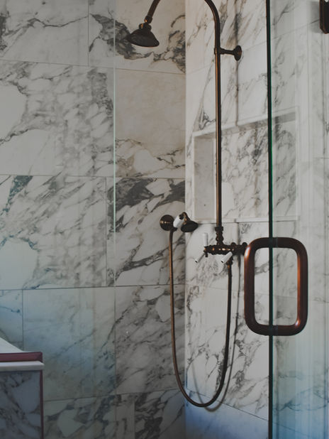 Marble shower with dark fixtures and glass door in a Centennial, Colorado bathroom.