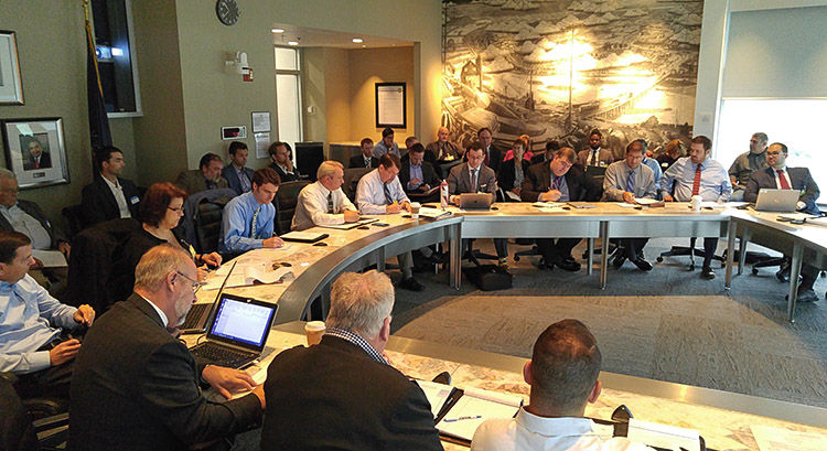 A group of business people assembled around tables for a coalition meeting.