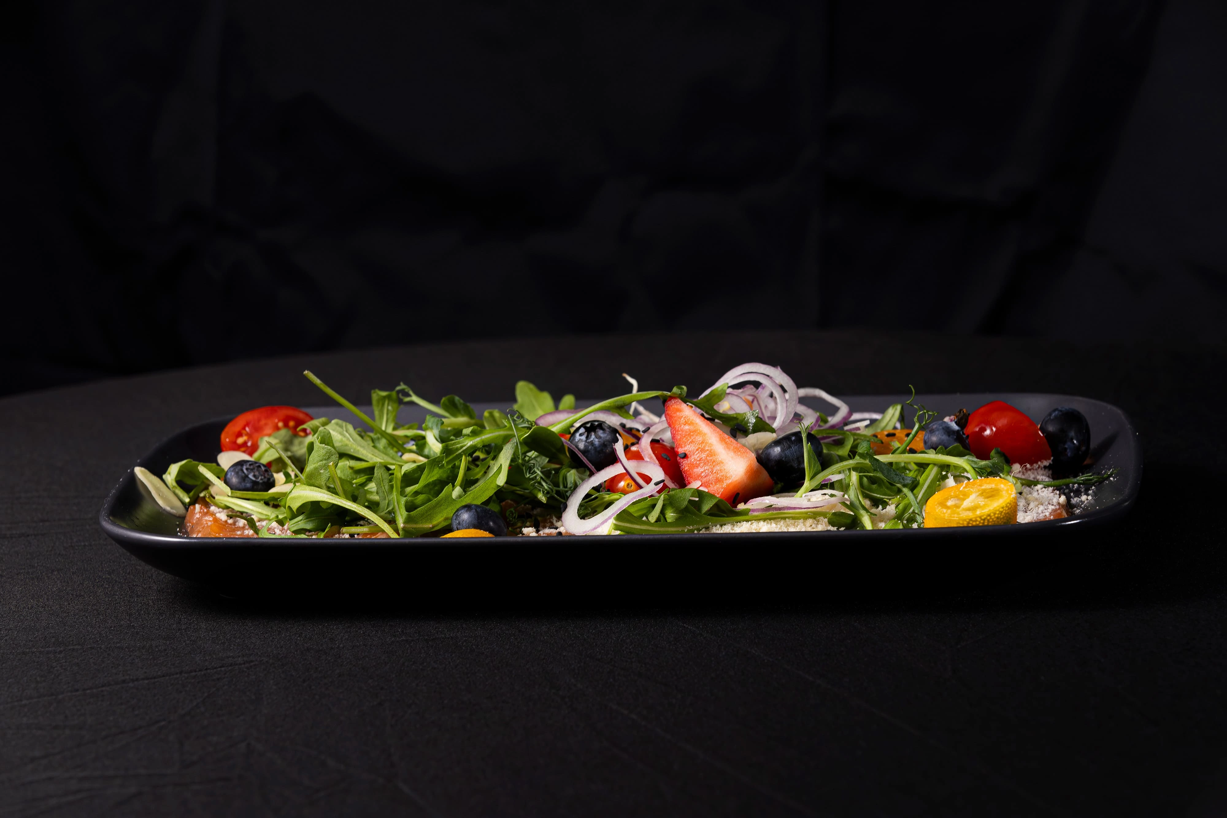 Salted salmon carpaccio with onion, parmesan, and cherry tomatoes.