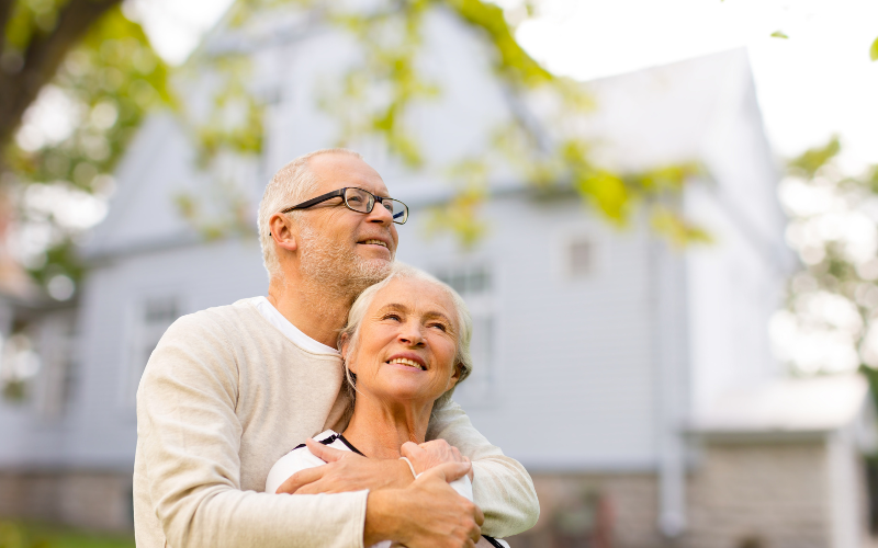 retired couple in front of house