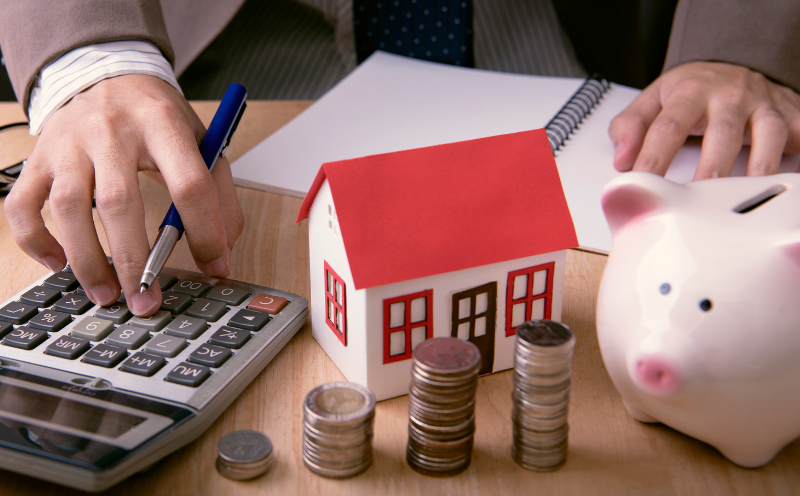 Homebuyer saving with calculator, money and piggy bank on table