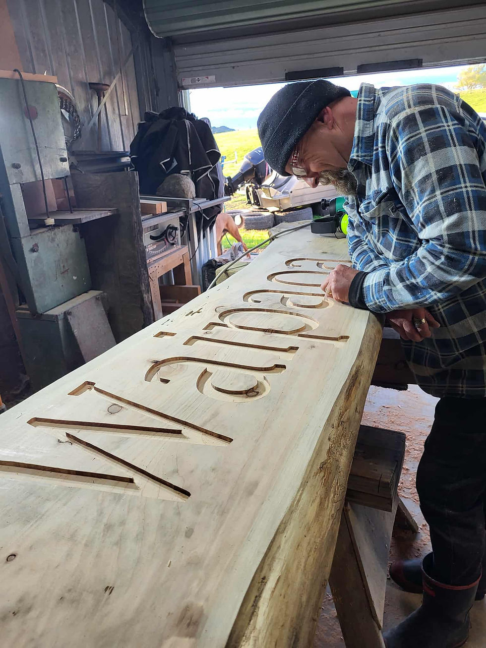 Grant from Slab Dezigns hand carving a wooden sign nz