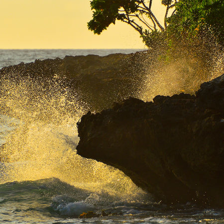 Ocean waves crashing against rocky shoreline during sunset near Turtle Bay on Oahu Hawaii