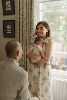 Mother gently cradling her sleeping newborn baby boy during a lifestyle newborn session in Hampstead.