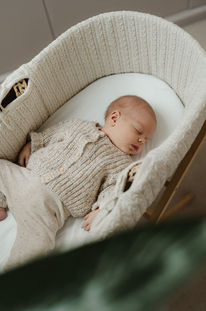 Newborn baby sleeping soundly in a woven basket during a natural lifestyle newborn session in Chelsea.