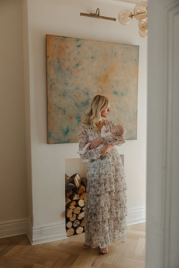In-home newborn photo shoot in Clapham Common featuring parents cuddling their newborn in a sunlit living room