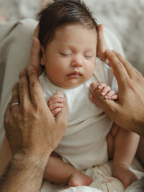 In-home newborn photographer North London capturing baby girl sleeping on mother's knees during a Kilburn photoshoot.