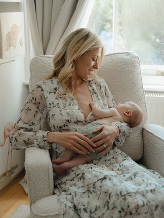 Mother gently rocking her sleeping 8-week-old son by a classic London Victorian bay window.