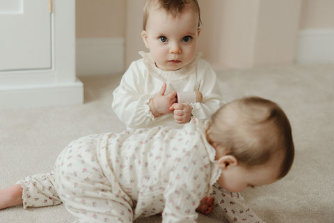 6-month old twin baby girls wearing a soft neutral clothing during a playful, unposed lifestyle baby photography session in South London.