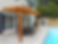 Photo of a cedar pergola coming off a window of a white brick house. The pergola is big enough to fit an outdoor dining table that seats 6 people. Pergola is poolside 