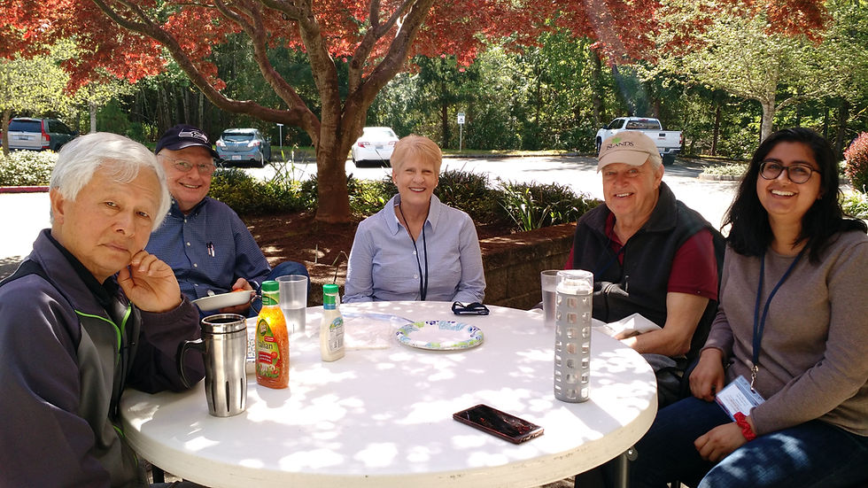 People at a cicular table outside under a tree