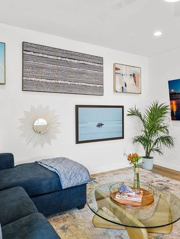 The Freeman project featuring a cozy living space with a blue couch, looking at a TV, and beach-themed wall art adding a fun and relaxed atmosphere.