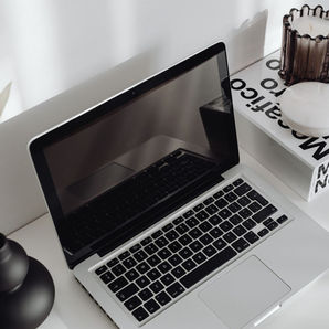 Open laptop surrounded by intentional desk decor, including a vase with a flower and a candle capturing the design-focused decision of when to use strips versus sections on your Wix site.