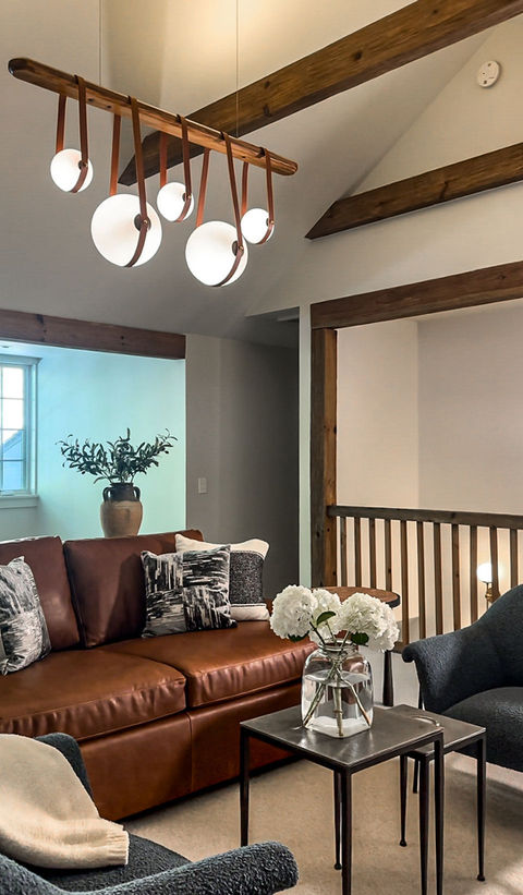 Side view of the upstairs living space featuring a leather couch, a coffee table with flowers, and a cozy, inviting atmosphere.