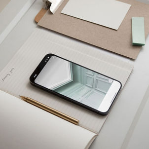 Smartphone showing a stylish accent wall, resting on a notebook with a pen nearby illustrating key steps to optimize your Wix site for mobile users.