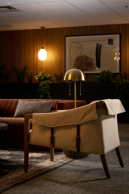 Law office waiting area featuring bamboo-style walls, pendant lighting, burgundy sofa, brown chair, and curated artwork.