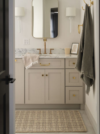 Primary bathroom with double vanity and checkered rug in a neutral, earth-toned luxury home in Rochester, Michigan