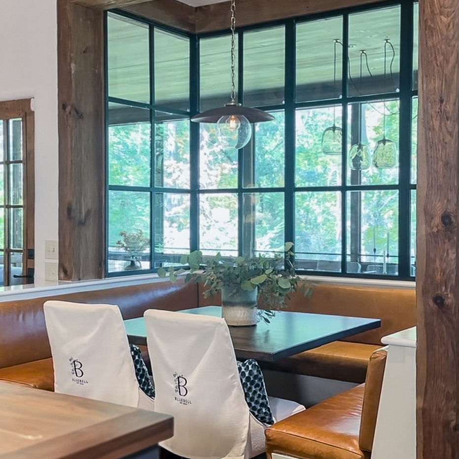 Kitchen nook area with bench seating and two monogrammed chairs. 