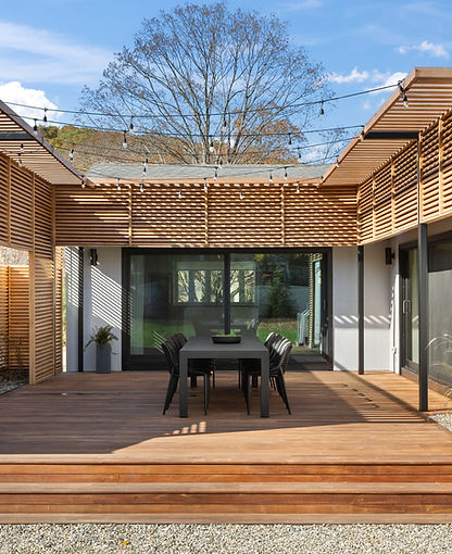 Warm and inviting outdoor patio area with pergola and black dining table to entertain guests.