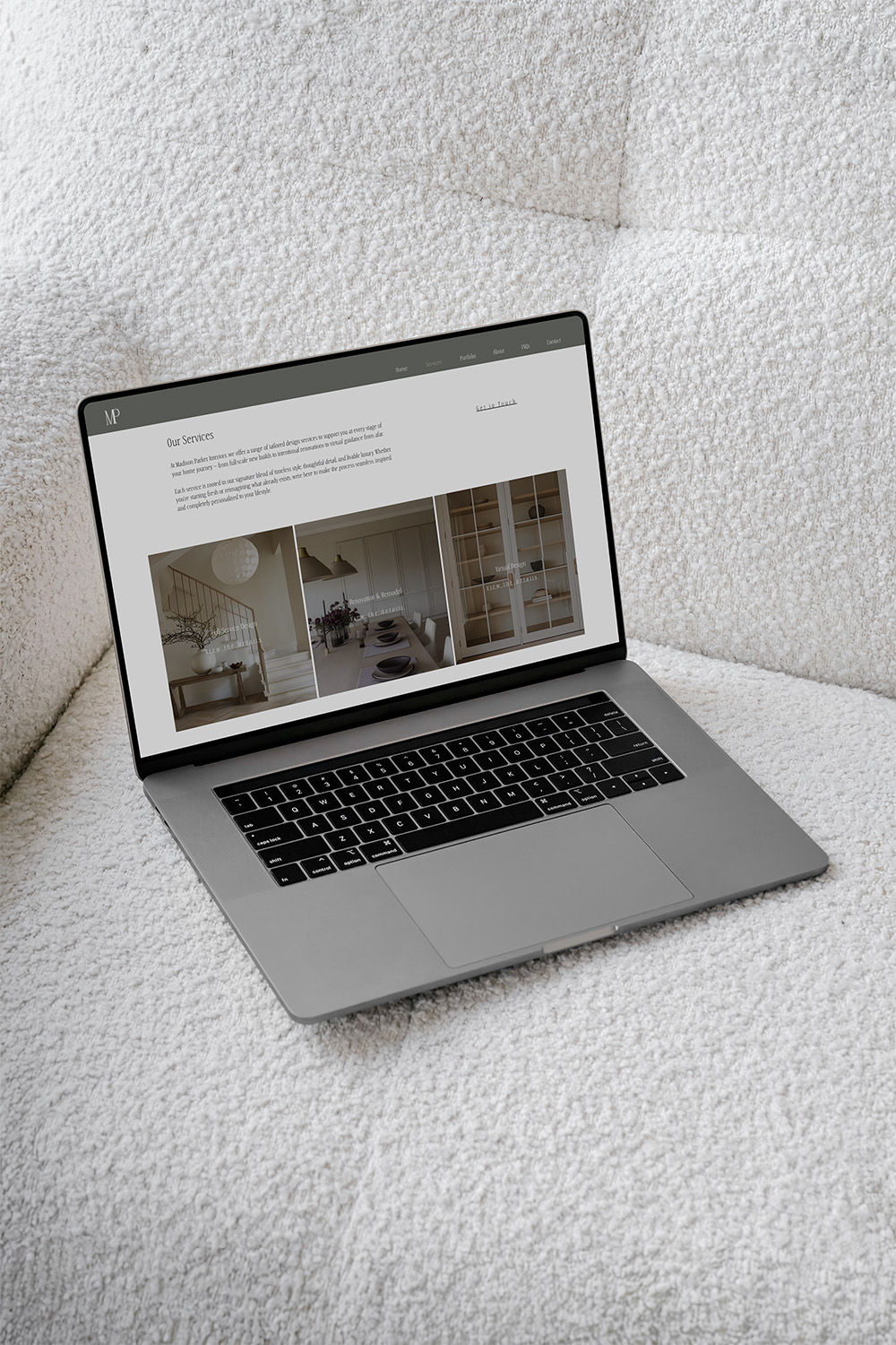 Laptop displaying the services page of Madison Parker Interiors, resting on a white couch, representing the beginning of a custom design journey with Cathleen Hall Creative through a discovery call.