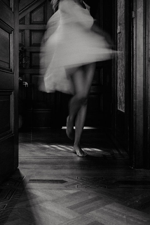 Editorial-style photo of a woman walking barefoot in a dress through a bright, architectural doorway - evoking the creative and elegant spirit of interior design.