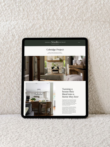 Laptop leaning against the back of a white couch showing a whole home renovation portfolio page from the Design Studio Detroit website, part of our custom website design portfolio for interior designers.
