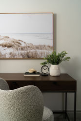 Office desk with landscape artwork above, styled with books, a small clock, and décor showcasing full-service interior design details.