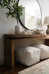 Entryway with wood console table, ottoman seating, circular mirror, and layered accessories styled for a Michigan residential interior design project.