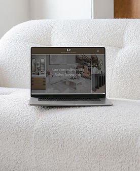 Laptop sitting on a white couch displaying the homepage of Anastasia Mitrovic Interiors, featured in a case study showcasing a custom interior design website by Cathleen Hall Creative.