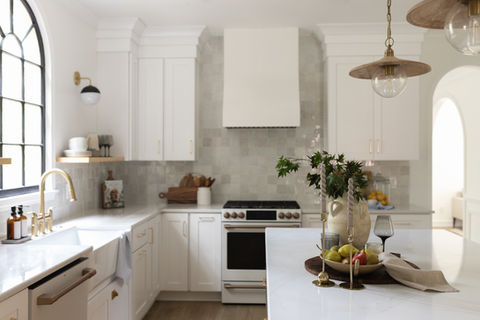 Green Ridge kitchen showcasing oak island with candles and fruit bowl, zellige tile backsplash, custom range hood, and arched doorway.