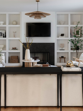 Riverhill living room in Sandy Springs, GA featuring black fireplace, white walls, built-in shelving with decor items, and white couches with two round coffee tables, creating a neutral, elevated luxury interior.